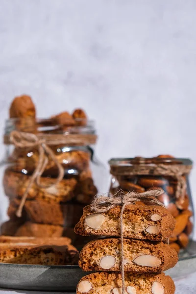 Traditional Italian cantuccini cookies with almonds in glass jar. Sweet dried biscuits. Homemade fresh Italian cookies cantuccini stacks and organic almond seeds. Healthy organic eating