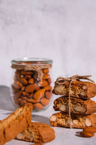 Traditional Italian cantuccini cookies with almonds in glass jar. Sweet dried biscuits. Homemade fresh Italian cookies cantuccini stacks and organic almond seeds. Healthy organic eating