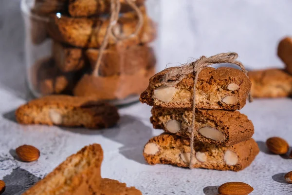 Traditional Italian cantuccini cookies with almonds in glass jar. Sweet dried biscuits. Homemade fresh Italian cookies cantuccini stacks and organic almond seeds. Healthy organic eating