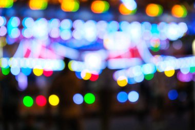 Odaklanamayan parlak ışıklar gece bir karnavalda yanıp sönüyor. Gece vakti eğlence parkı Bokeh Işıkları. Gece hayatı eğlencesi