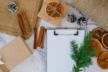 Noel tatiline hazırlanan bir kadın. Hediye listesi yazıyorum. Yeni yıl hediyeleriyle dolu bir kutu, el işi kağıdına sarılmış ve köknar dalı, kuru portakal dilimleri, tarçın çubukları ile süslenmiş. El yapımı Çevre dostu