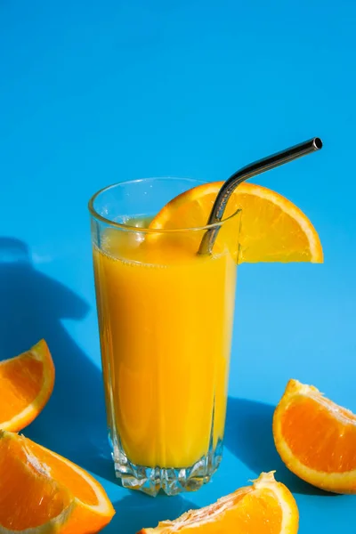 Стакан свежевыжатого апельсинового сока с эко-металлом, пьющим соломинку нарезанные фрукты на синем фоне. Фруктовый сок, свежая простуда. Летом прохладительные напитки. Чистое питание, потеря веса, здоровое питание — стоковое фото