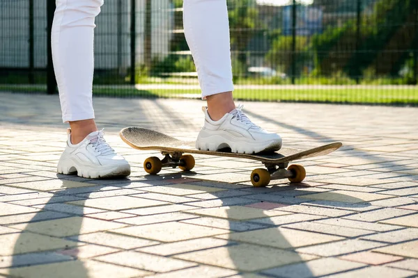 Close up Dívka skateboardista nohy skateboarding při západu slunce. sluneční podsvícení a svoboda vzbouřit nezávislý koncept. Den strávený aktivním koníčkem tabule. — Stock fotografie