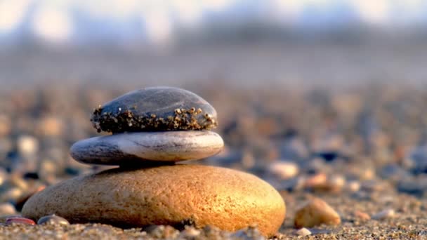 Balansowanie na oceanicznej plaży. Piramida kamieni na piaszczystym brzegu. Stabilny stos lub stos w miękkiej ostrości z bokeh, zbliżenie. Zen równowaga, minimalizm, harmonia i pokój — Wideo stockowe