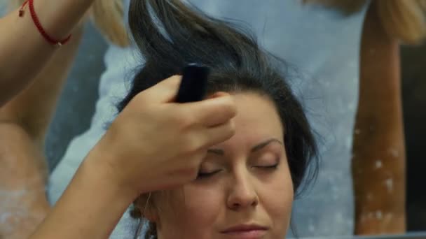 用发胶做发型，准备舞会。美容院内无法辨认的妇女长发用卷发钳做发型的造型师的近照. — 图库视频影像