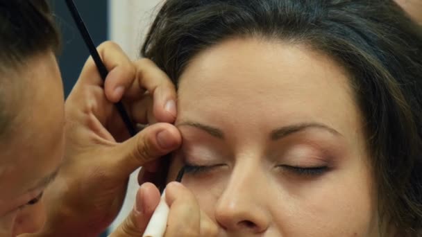 Makeup artist tillämpa makeup på ögonen på ung kvinna. Professionell makeup artist tillämpa makeup för brud. Ogräsbildning — Stockvideo