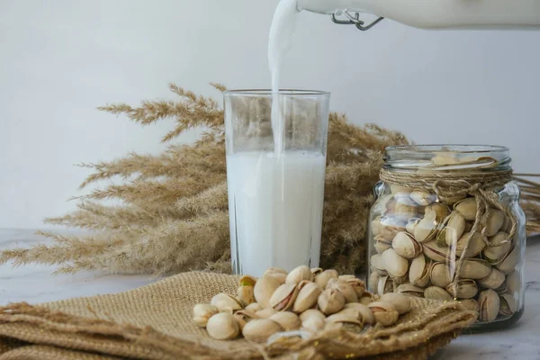Rostlinné mléko se nalije do sklenice Pistachio mléko bez laktózy pro dietní výživu. Alternativní jídlo a vegetariánství. Dietní mléko, vegetariánské jídlo. Bez lepku. — Stock fotografie