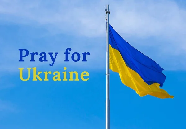 ORA POR UCRANIA texto sobre bandera nacional ucraniana ondea en el viento contra el cielo azul. El símbolo nacional de los ucranianos - azul y amarillo. No hay guerra. Protesta de guerra contra la invasión rusa de —  Fotos de Stock