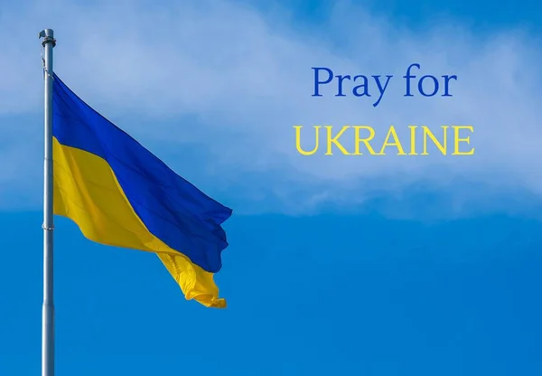 ORA POR UCRANIA texto sobre bandera nacional ucraniana ondea en el viento contra el cielo azul. El símbolo nacional de los ucranianos - azul y amarillo. No hay guerra. Protesta de guerra contra la invasión rusa de —  Fotos de Stock