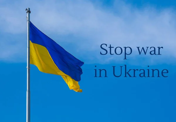 ОСТАНОВИТЬ ВОЙНА В УКРАИНЕ текст на украинском государственном флаге трепещет на ветру против голубого неба. Государственный символ украинского народа - синий и желтый. Никакой войны. Протест против вторжения России — стоковое фото