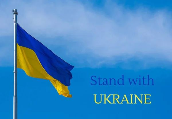 СТАТТІ З УКРАЇНСЬКОГО текстом на українському національному прапорі пурхають вітром на синє небо. Національний символ україніанського народу - синій і жовтий. Ніякої війни. Воєнний протест проти вторгнення Росії — стокове фото