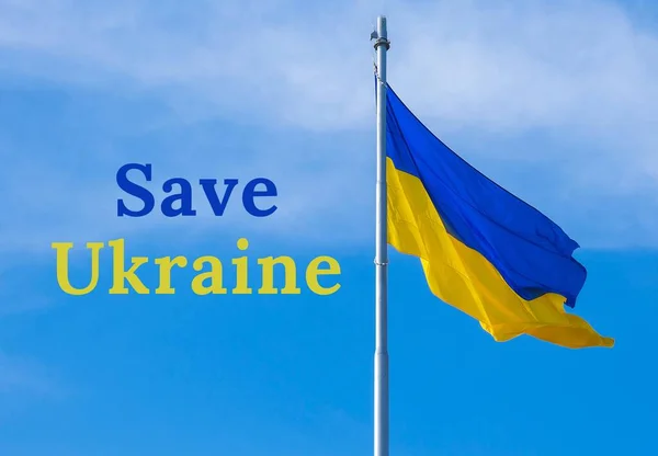 青い空に対して風の中でウクライナの国旗のフルートにUKRAINEテキストを保存します。ウクライナ人の国民のシンボル-青と黄色。戦争はない。ロシアのウクライナ侵攻に対する戦争抗議. — ストック写真