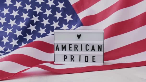 Αργή κίνηση κυματίζει αμερικανική σημαία φόντο. Lightbox με κείμενο AMERICAN PRIDE Σημαία των Ηνωμένων Πολιτειών της Αμερικής. 4η Ιουλίου Ημέρα Ανεξαρτησίας. ΗΠΑ πατριωτισμός εθνική εορτή. Ο Ούσα περήφανος. — Αρχείο Βίντεο