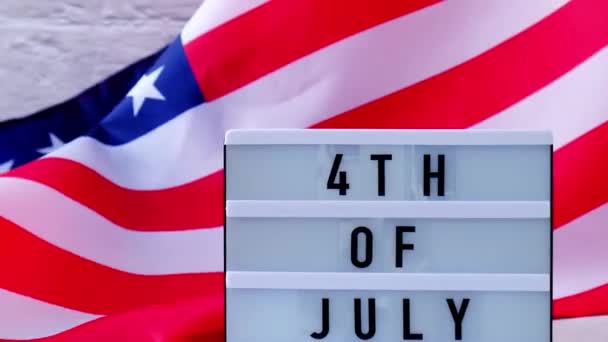4k Waving American Flag Hintergrund. Leuchtkasten mit Text 4TH OF JULY Flagge der Vereinigten Staaten von Amerika. 4. Juli, Unabhängigkeitstag. Nationalfeiertag des Patriotismus in den USA. USA stolz. — Stockvideo