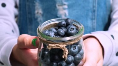 Taze yaban mersinli kaseyi tutan kadın. Yavaş çekim hasat konsepti. Dişi eller böğürtlen topluyor. Sebze bahçesi kulübesi, hasat, bahçe işleri.