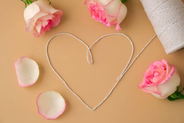 Bej arka planda kalp şeklinde beyaz pamuk ipli yumuşak pembe güller. Minimum trend kompozisyonu. Tarafsız toprak tonları. Sevgililer Günü için tebrik kartı. Anneler Günü.