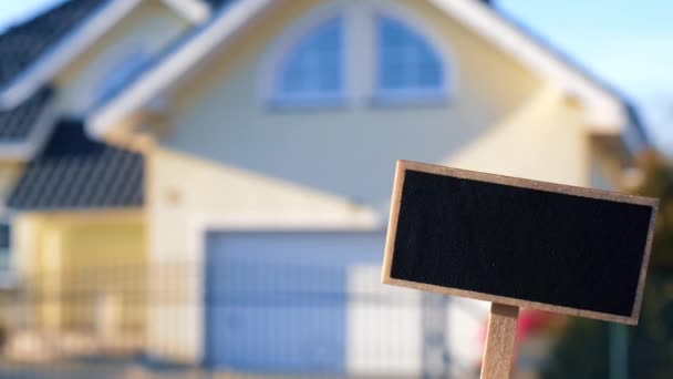 空白黑色公告栏与新建的房屋相抗衡,空模型模板黑板标签家庭出租.房子待售。在新家前面签名。重新定位运动 — 图库视频影像