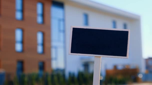 空白黑色公告栏与新的公寓楼相对照,空模仿模板黑板标签家庭出租.公寓待售。在新家前面签名。B.广告 — 图库视频影像