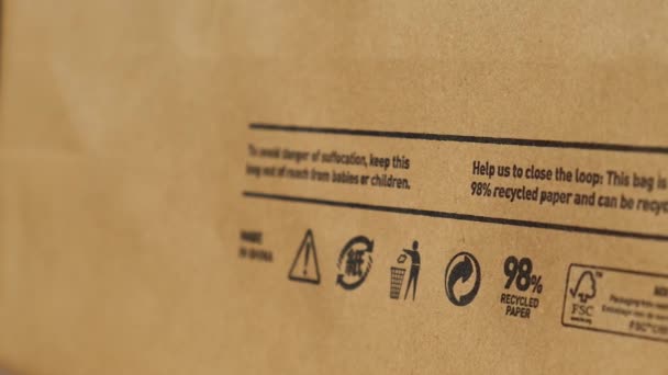 Újrahasznosító zsák Pap tábla és egyéb ökocímke közeli áttekintése barna papírzacskón, amely 100 újrahasznosítható és újrahasznosítható spbd. A szimbólum papírt és kartont jelöl. Koncepció: ökológia környezeti biztonság — Stock videók