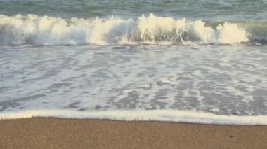 Okyanus dalgaları kumsalı yıkar. Seyahat yaz konsepti. Plajda tatil. Akdeniz 'in dalgaları kumlu kumsala doğru gün ışığında akıyor..