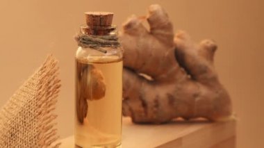 Cam şişe zencefil yağı, bej arka planda zencefil kökü. Sağlıklı yemek yeme konsepti. Zingiber officinale Temel Yağ. Cilt bakımı, vücut ve saç bakımı için doğal kozmetik malzemeleri.