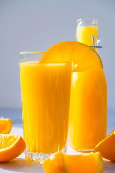 Glasflaska Med Färsk Pressning Apelsinjuice Med Skivade Frukter Konkret Bakgrund — Stockfoto