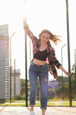 Sokakta kaykay süren bir kadın. Uzun kaykaylı kaykaycı kız. Gün batımında havalı bir bayan kaykaycı. Kaygısız kadın patenci 20 'li yaşlarda özgürlüğün tadını çıkarıyor gençlik hobisi