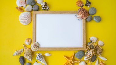 Fotokopi alanı, deniz kabukları, çakıl taşları, sarı arka plan için kompozisyon çerçevesi. Boşluk, üst görünüm, durgun hayat, düzlük. Deniz seyahati konsepti turizm ve tatil beldeleri. Yaz tatili