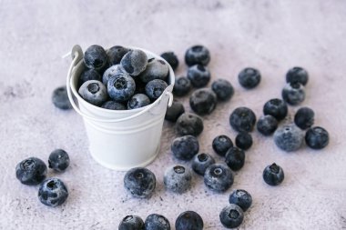 Donmuş yaban mersinleri beton arka planda küçük bir kovada. Sağlıklı organik mevsimlik meyve arka planı. Organik yiyecekler. Hasat, kış için yemek hazırlamak. Süper yemek. Güzel görüş. Gözlerini açık tut.