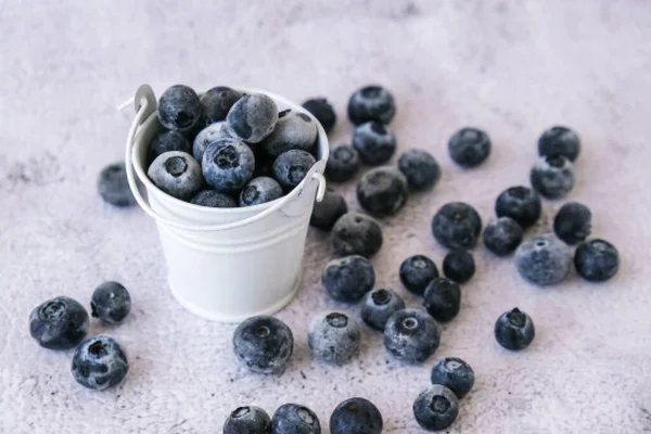 Donmuş yaban mersinleri beton arka planda küçük bir kovada. Sağlıklı organik mevsimlik meyve arka planı. Organik yiyecekler. Hasat, kış için yemek hazırlamak. Süper yemek. Güzel görüş. Gözlerini açık tut.