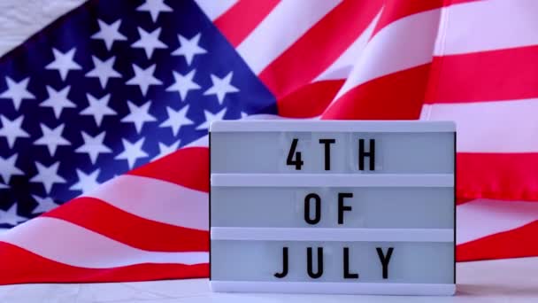 4k κυματίζει αμερικανική σημαία φόντο. Φωτεινό κουτί με κείμενο της 4ης Ιουλίου Σημαία των Ηνωμένων Πολιτειών της Αμερικής. 4η Ιουλίου Ημέρα Ανεξαρτησίας. ΗΠΑ πατριωτισμός εθνική εορτή. Ο Ούσα περήφανος. — Αρχείο Βίντεο