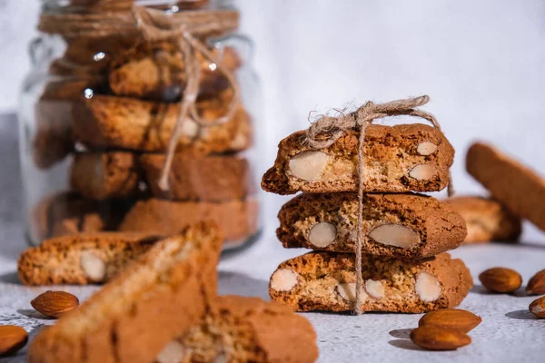 Traditional Italian cantuccini cookies with almonds in glass jar. Sweet dried biscuits. Homemade fresh Italian cookies cantuccini stacks and organic almond seeds. Healthy organic eating