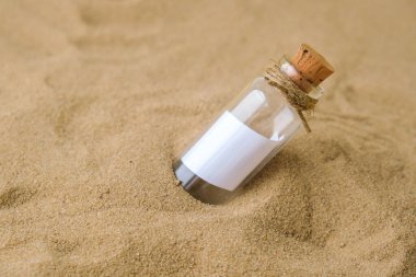Plajda şişede bir mektup. Ada yaşam tarzı. Cam bir şişede, kumdaki mantarlı kağıt bir mesaj. Kurtuluşla ilgili not, lütfen yardım et. SOS konsepti. Uzayı kopyala Model boş
