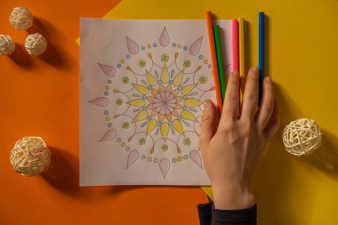 Stresle savaşmak için kadın mandalaları boyuyor. Rahatlama hobisi zihinsel refah ve sanat terapisi. Kadın eskiz çiziyor, boyama sayfalarının meditasyonunu yapıyor. Sanatla kendini ifade etme 