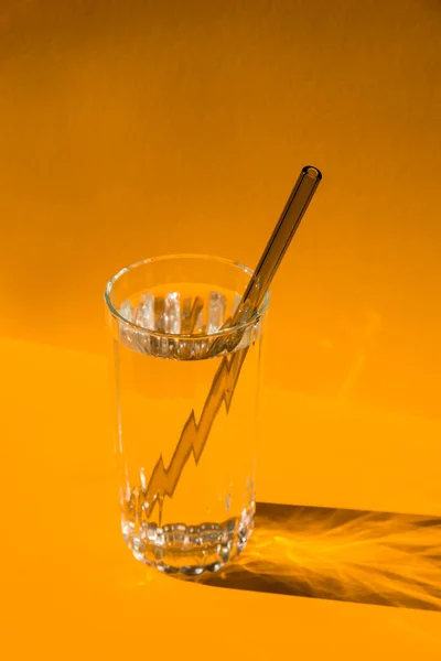 Reusable glass Straws in Glass with water on yellow background Eco-Friendly Drinking Straw Set with cleaning brush. Zero waste, plastic free concept