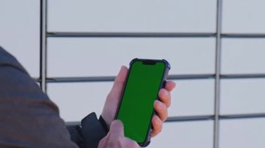 Unrecognizable woman holding mobile phone with chroma key using app next to shopping locker. Contactless safety way of delivery. New technology pick point service great for online stores