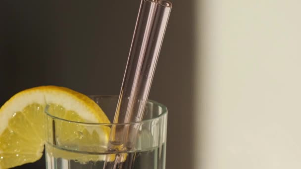 Glas water met vers citroensap met herbruikbaar glas Rietjes Detox koud tonic water met zonnige citroenschijfjes Low-waste lifestyle Eco-vriendelijk Drinkstro — Stockvideo