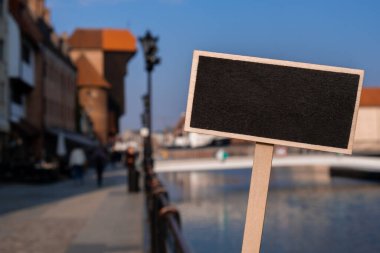 Motlawa nehrinin üzerindeki Gdansk güzel eski kasabasına karşı boş model karatahta etiketi. Zuraw Turnası ve Polonya 'nın Gdansk kentinin renkli gotik cepheleri. Polonya Pomerania 'nın tarihi başkenti Gdansk' ı ziyaret edin.