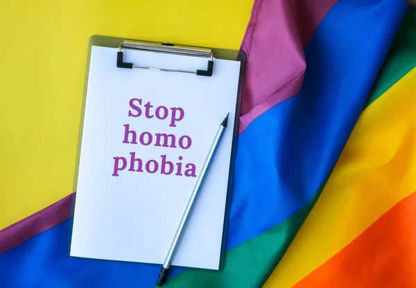 Tęczowa flaga z tekstem STOP HOMOPHOBIA notatka papierowa. Tęczowa flaga Igbtq wykonana z jedwabiu. Symbol miesiąca dumy LGBTQ. Równe prawa — Zdjęcie stockowe
