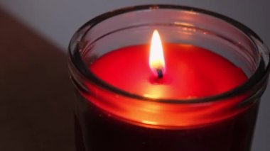 Kırmızı mum, cam bir şamdanda yanıyor. Kırmızı mum, alev alev yanan alevlerle yanıyor. Karanlık arka planda ateş dilleri. Romantik ruh hali konsepti. Monokrom duvar kağıdı