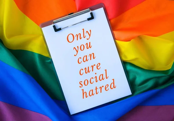 Bandeira do arco-íris com texto SOMENTE VOCÊ PODE CURE SOCIAL HATRED mensagem nota de papel. Rainbow lgbtq bandeira feita de material de seda. Símbolo do mês de orgulho LGBTQ. Igualdade de direitos — Fotografia de Stock