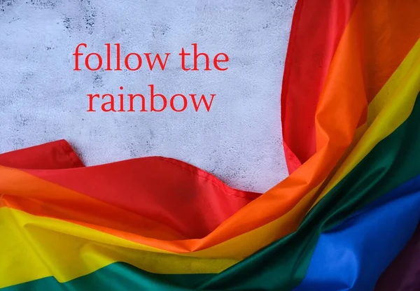 Tęczowa flaga z tekstem Śledź wiadomość RAINBOW. Tęczowa flaga Igbtq wykonana z jedwabiu. Symbol miesiąca dumy LGBTQ. Równe prawa — Zdjęcie stockowe