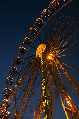 Gece Dönme dolabın ışıkları. Dönme dolapta yanıp sönen neon renkli ışıklar. Geceleyin eğlence parkı. Eğlence ve eğlence. Karnaval 'da dinlenme atlıkarınca. Renkli dönme dolap