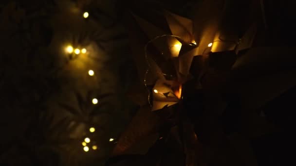 Kese kağıdından çantaları olan kağıt yıldızlar, geceleri Noel için kağıt süslemeler yapan. Çelenk ışıl ışıl parlıyor Ekolojik ve sürdürülebilir bir kutlama — Stok video