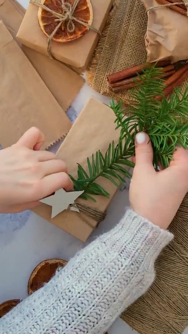 Kvinna gör Box med nyår gåvor, insvept i hantverk papper och dekorerad med gran gren. Semester och gåvor koncept. Handgjort Miljövänligt alternativ grön julklappar noll avfall — Stockvideo