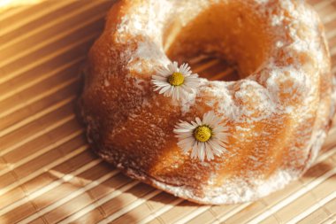 Kek papatya çiçeğiyle süslenmiş, kır tarzında. Otantik fotoğraf. Paskalya konsepti tebrik kartı geçmişi. Güneş ışınları ev yapımı fırın konsepti. Yaz, bahar zamanı tarifi