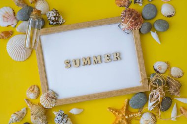 Kompozisyon kağıdının beyaz metni YAZ, deniz kabukları, çakıl taşları, sarı arka plan modeli. Boşluk, üst görünüm, durgun hayat, düzlük. Deniz seyahati konsepti turizm ve tatil beldeleri. Yaz tatili