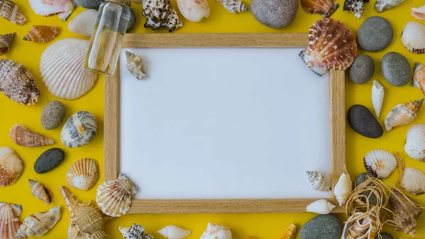 Fotokopi alanı, deniz kabukları, çakıl taşları, sarı arka plan için kompozisyon çerçevesi. Boşluk, üst görünüm, durgun hayat, düzlük. Deniz seyahati konsepti turizm ve tatil beldeleri. Yaz tatili