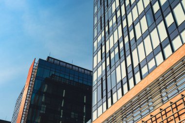Gökyüzü arka planında cam cepheli modern ofis binası. Ofis binasının şeffaf cam duvarı, turuncu süslemeli. Modern Avrupa binasının dış cephesi