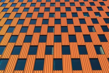 Gökyüzü arka planında cam cepheli modern ofis binası. Ofis binasının şeffaf cam duvarı, turuncu süslemeli. Modern Avrupa binasının dış cephesi